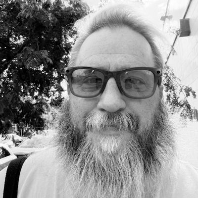 Jason, founder of New To Northern Liberties, a bearded man in glasses on a city sidewalk